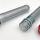 A couple of plastic soda bottle preforms, one with its red cap removed.